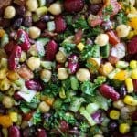 fresh veggies and mixed beans with herbs in wooden bowl.