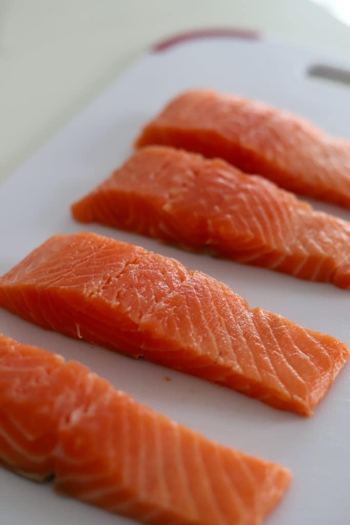 raw salmon fillets on cutting board.