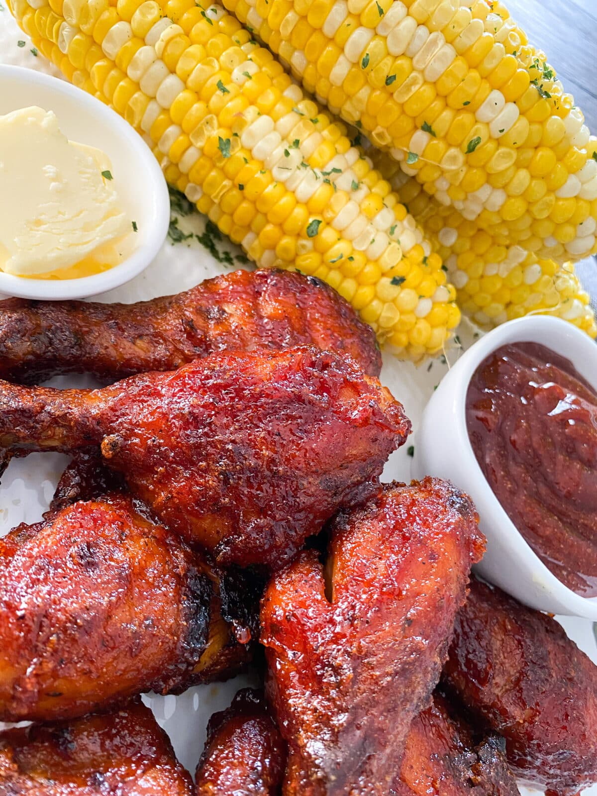 Grilled chicken drumsticks coated in smoky hickory BBQ sauce, served with corn on the cob, butter, and extra barbecue sauce for dipping.