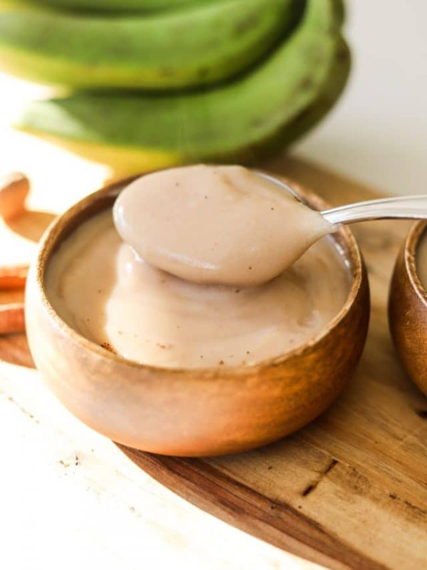 jamaican green banana porridge in wooden bowl with spoon.