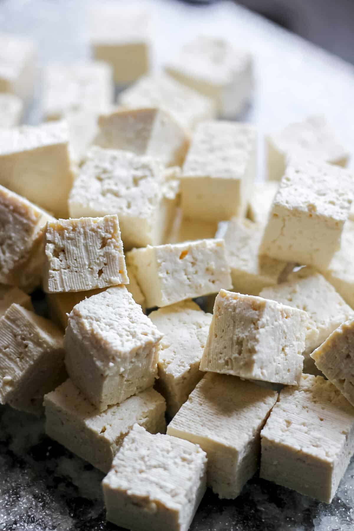 Freshly cubed tofu ready for cooking on a kitchen counter.