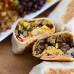sliced tex mex breakfast burrito with burrito fillings in the background