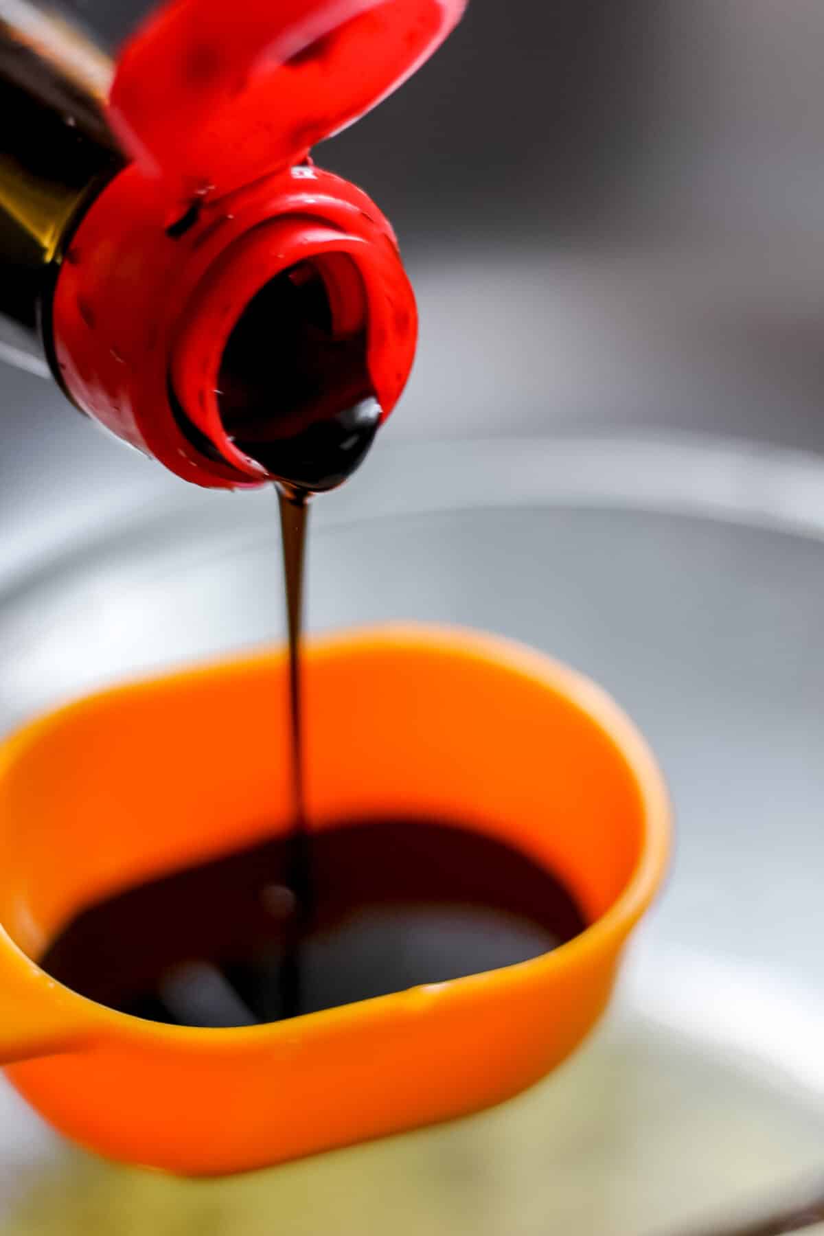 soy sauce being poured into a measuring cup