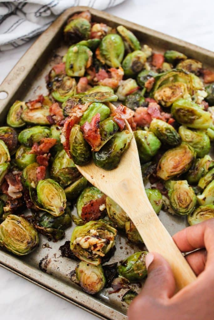 wooden spoon with roasted brussels sprouts with bacon.