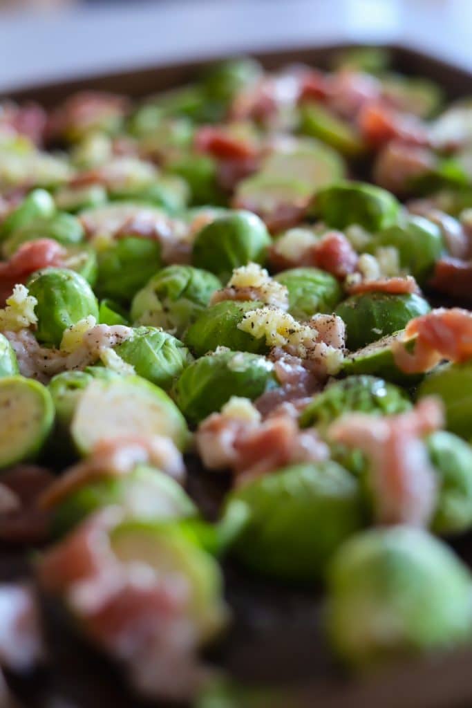 brussels sprouts, garlic and bacon seasoned with salt and pepper on baking tray.