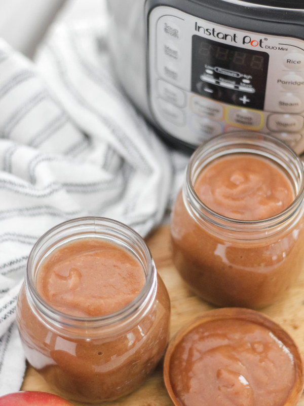 2 jars of apple butter in mason jars on wooden board with insta pot in background