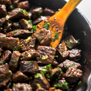 Easy Garlic Butter Steak Bites in Skillet with Wooden Spoon