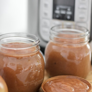2 jars of apple butter in mason jars on wooden board with insta pot in background