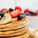 Gluten Free Banana Oat Protein Pancakes stack of 4 with fruit and syrup on top