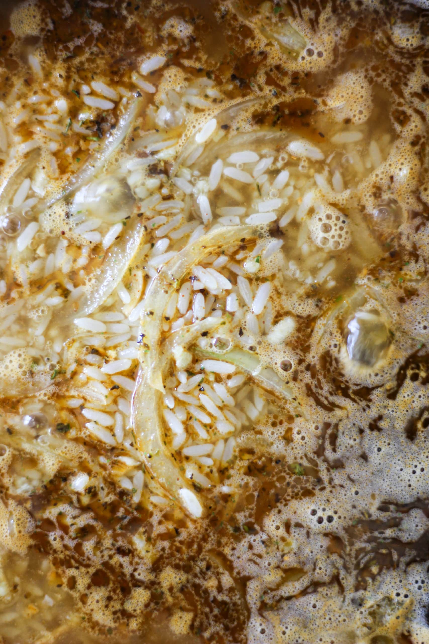 cajun rice with onions, garlic, chicken broth in black skillet.