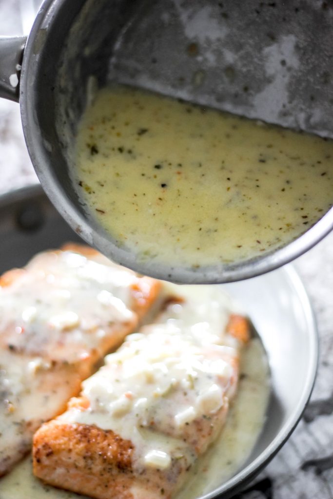 Creamy Lemon Butter Sauce in Saucepan being poured over pan seared salmon
