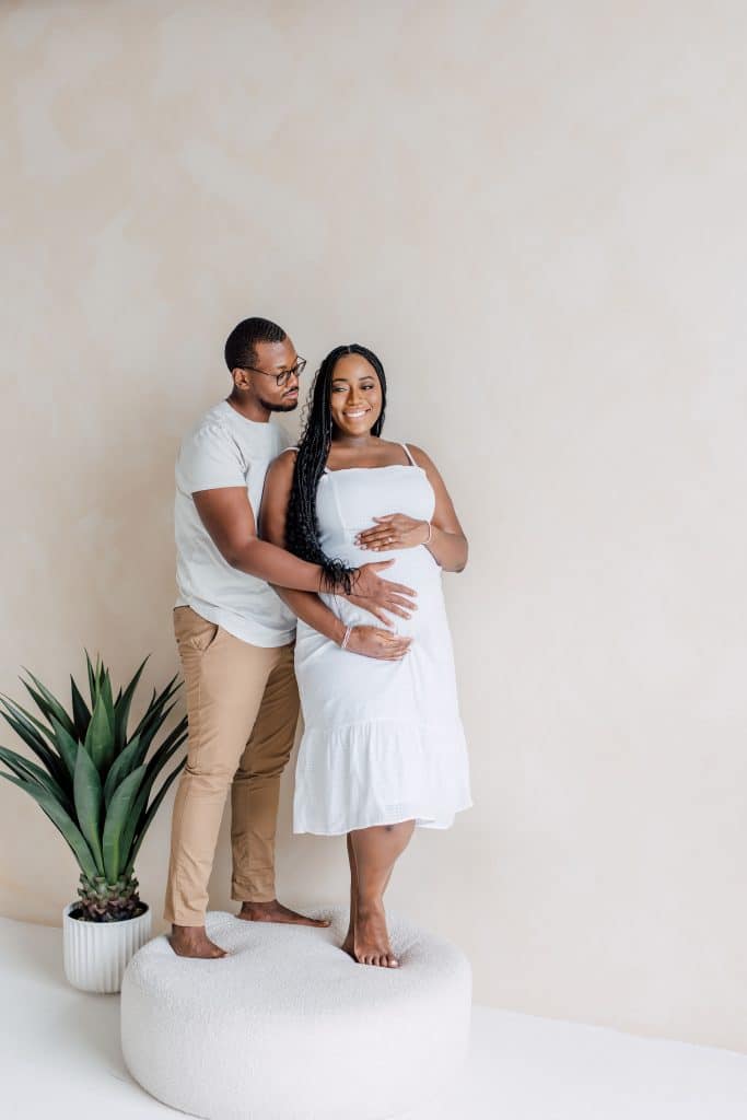 Husband and Pregnant Wife Standing on Couch Hugging