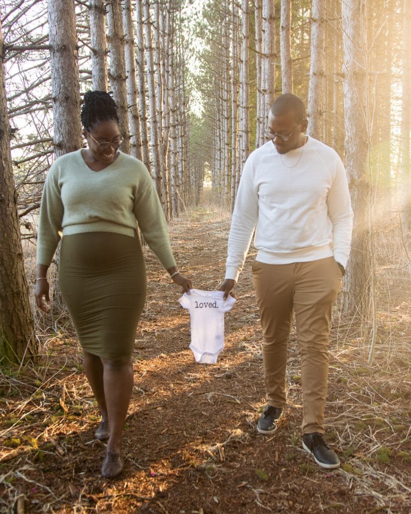 Husband and Wife Walking in Woods with White Loved Onesie