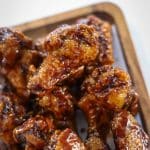 honey garlic chicken wings on wooden plate.