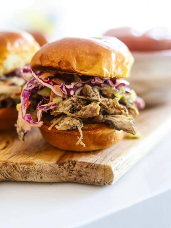 jerk chicken sandwich with slaw on wooden board.