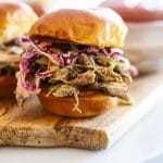 jerk chicken sandwich with slaw on wooden board.
