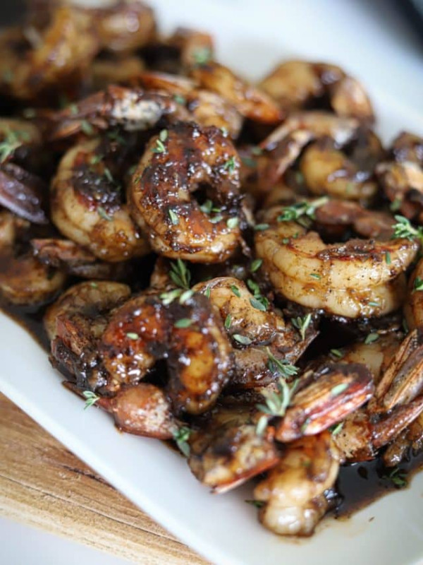 honey jerk shrimp on white plate with a garnish of fresh thyme.