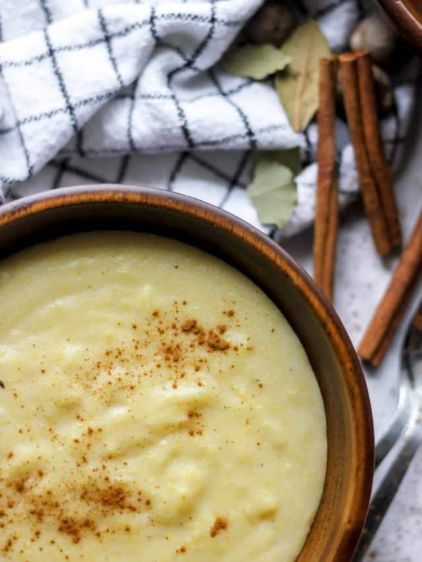 jamaican cornmeal porridge in wooden bowl with a dash of cinnamon.