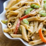 rasta pasta in a white bowl on a wooden plank.