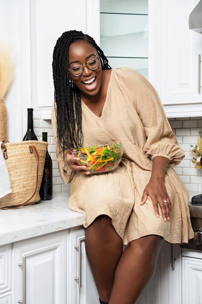 taneisha in brown dress sitting on counter smiling.