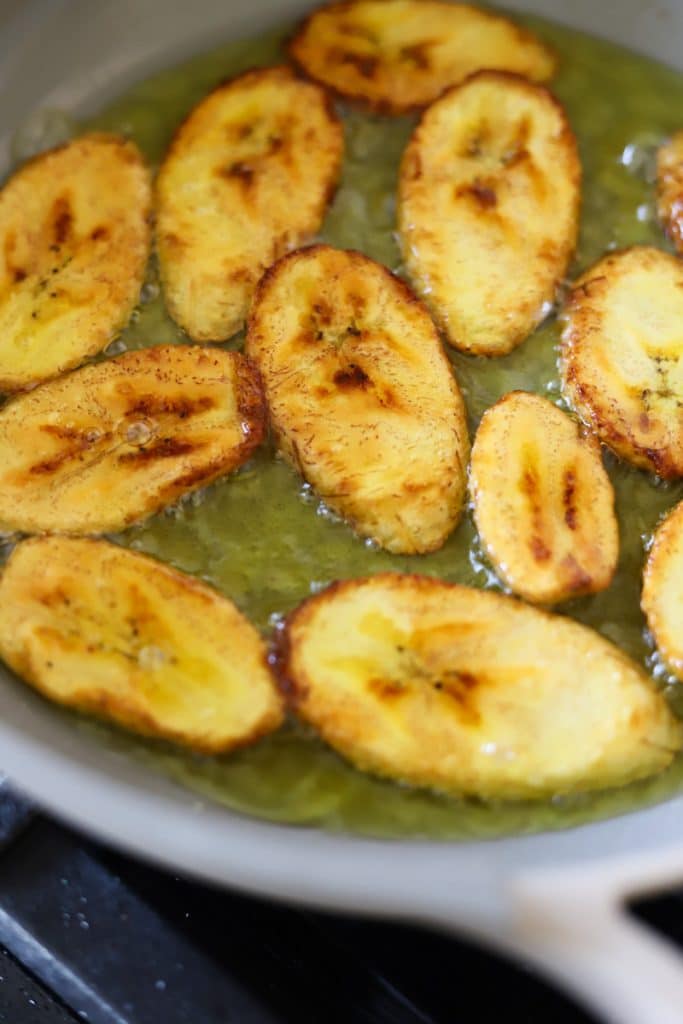 slices of plantain frying in pan.