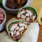 jerk turkey wrap cut in half with jerk turkey on wooden board.