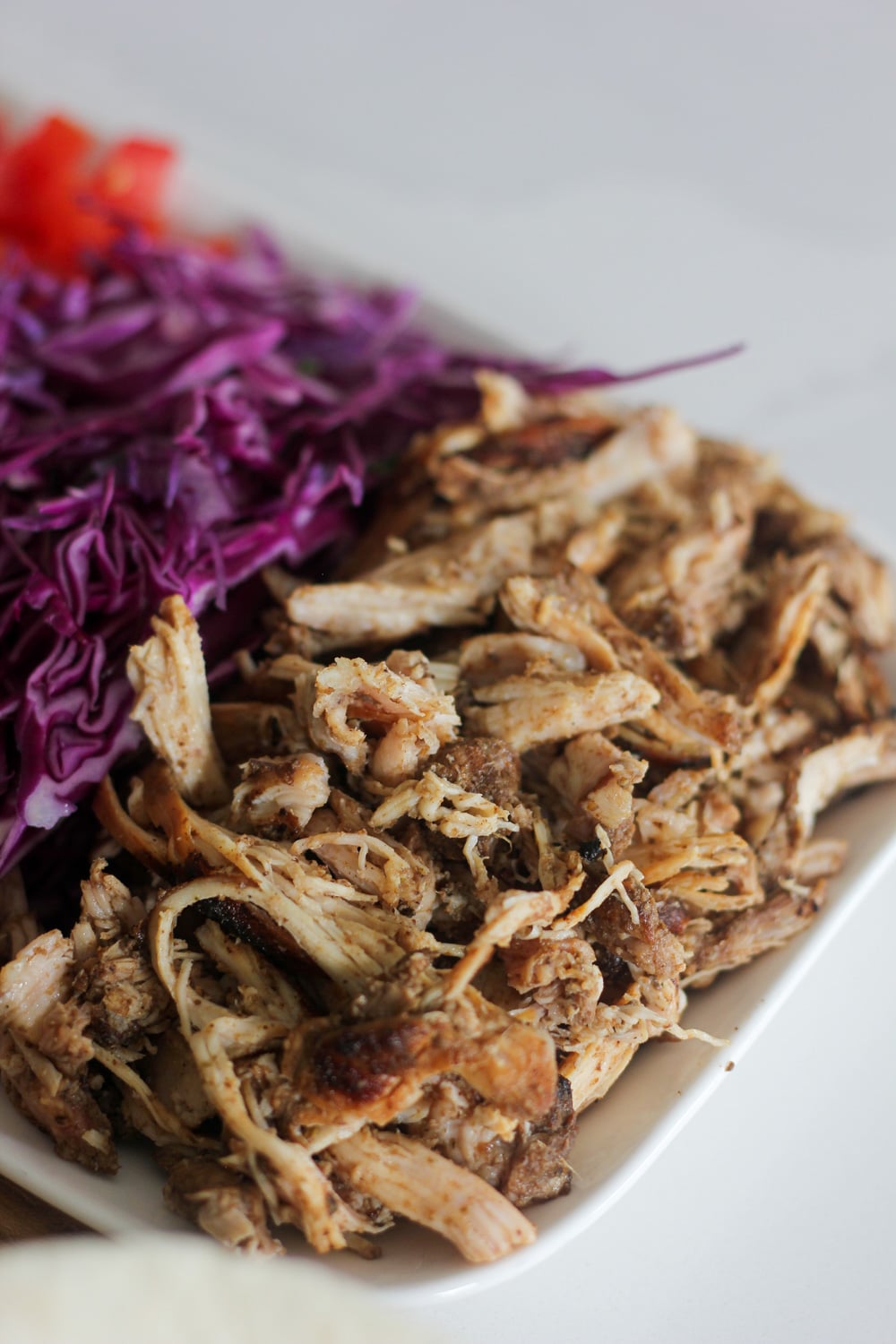 Shredded Jamaican jerk chicken for tacos resting on white plate