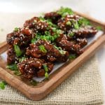 soy garlic chicken garnished with sesame seeds and green onions.