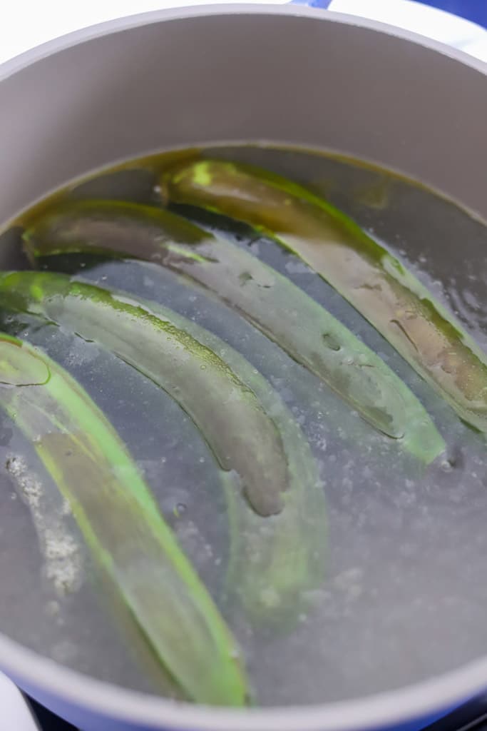 green bananas submerged in a large pot of water
