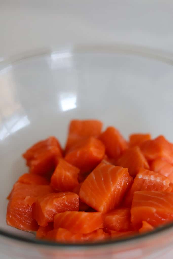 raw salmon cut into cubes in glass bowl.