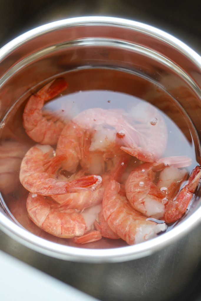 large raw shrimp defrosting in cold water.