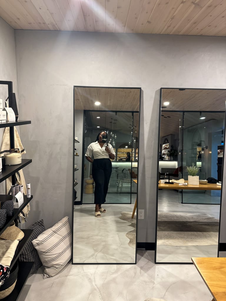 a woman posing in a mirror in an upcsale, modern shop
