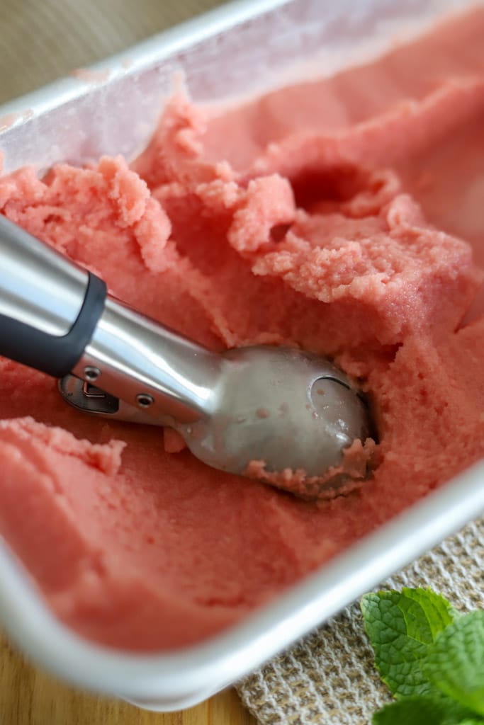 an ice cream scoop inserted in a container full of sorbet