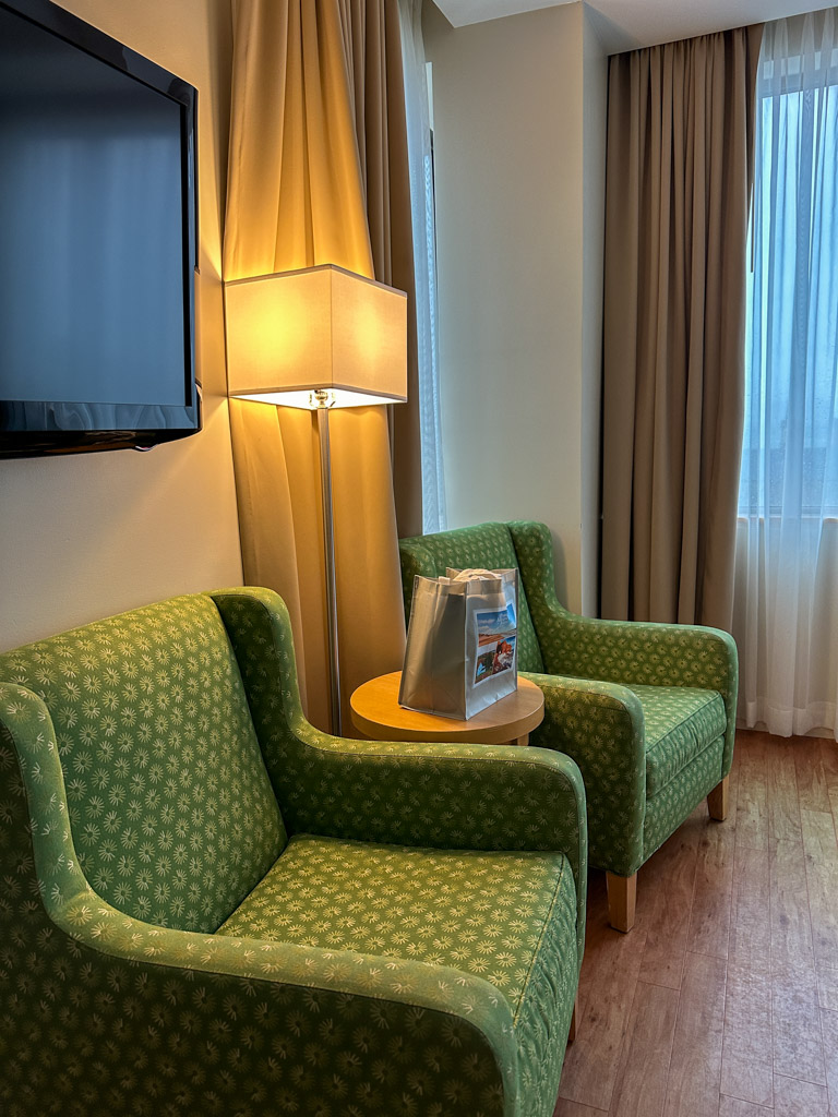 The Holman Grand Hotel room lounge area with two green chairs.