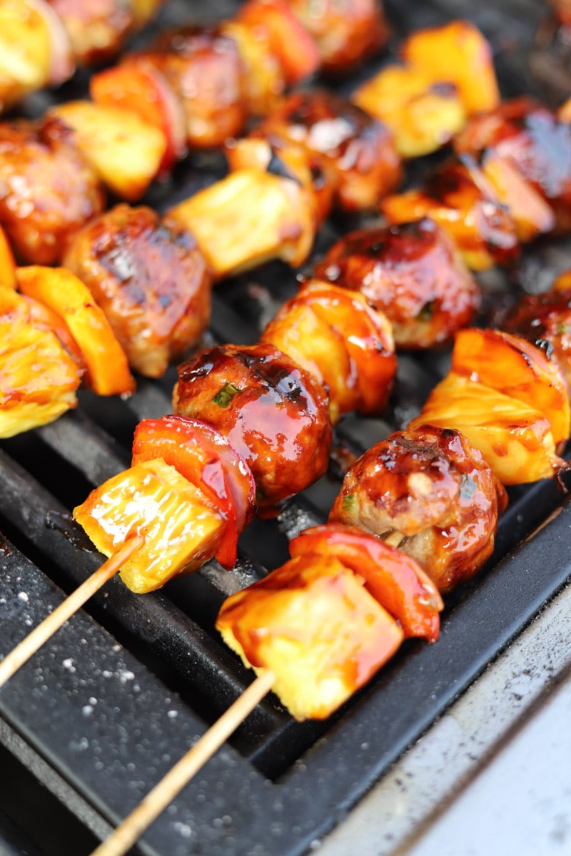 grilled meatball skewers with sweet and sour glaze on grill.