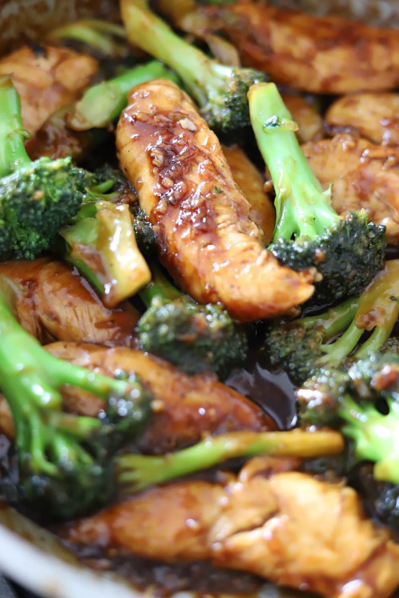 Chicken and broccoli simmering in sauce in a skillet.