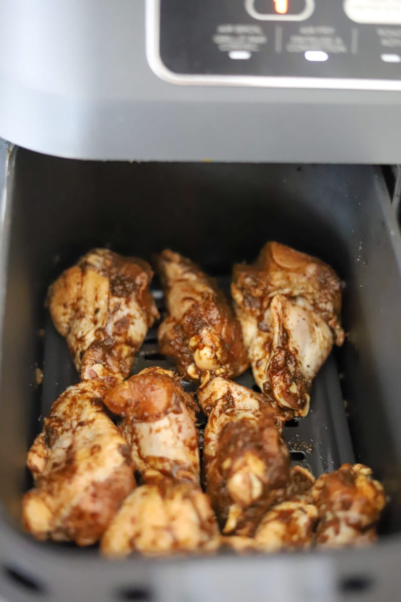 seasoned jerk chicken wings in an air fryer basket