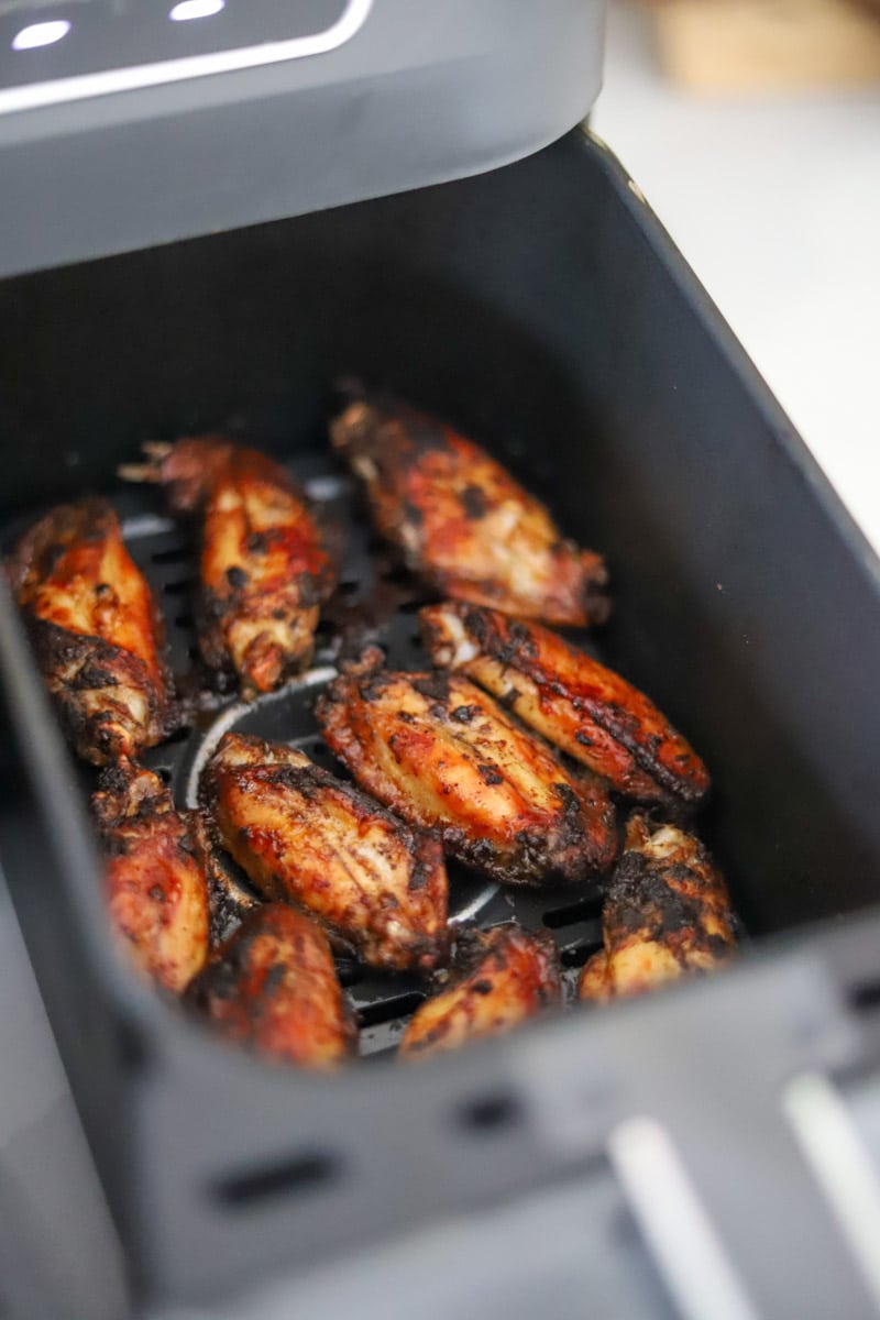 fully cooked jerk chicken wings in an air fryer basket