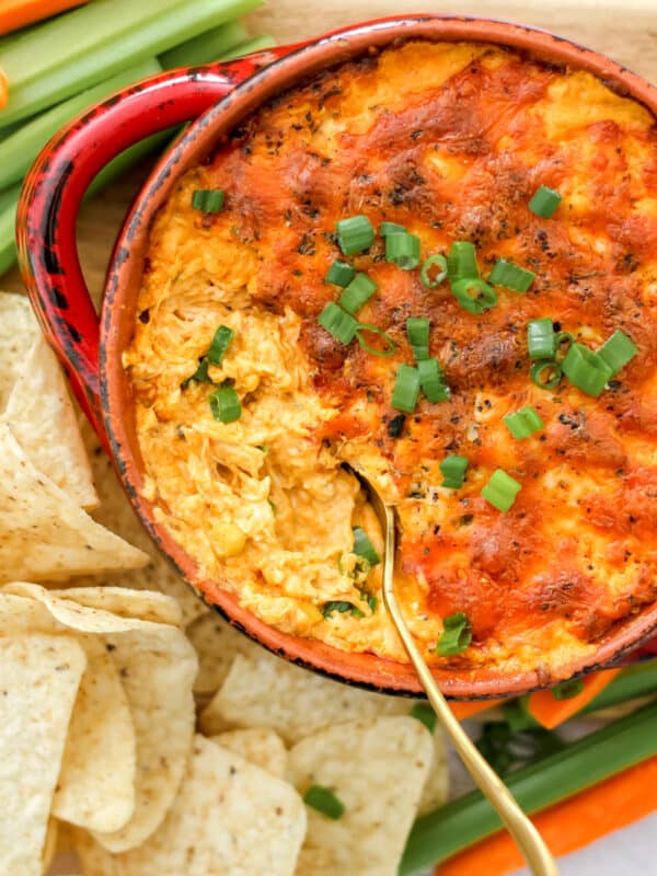 a large dish full of Franks buffalo chicken dip surrounded by tortilla chips and veggies