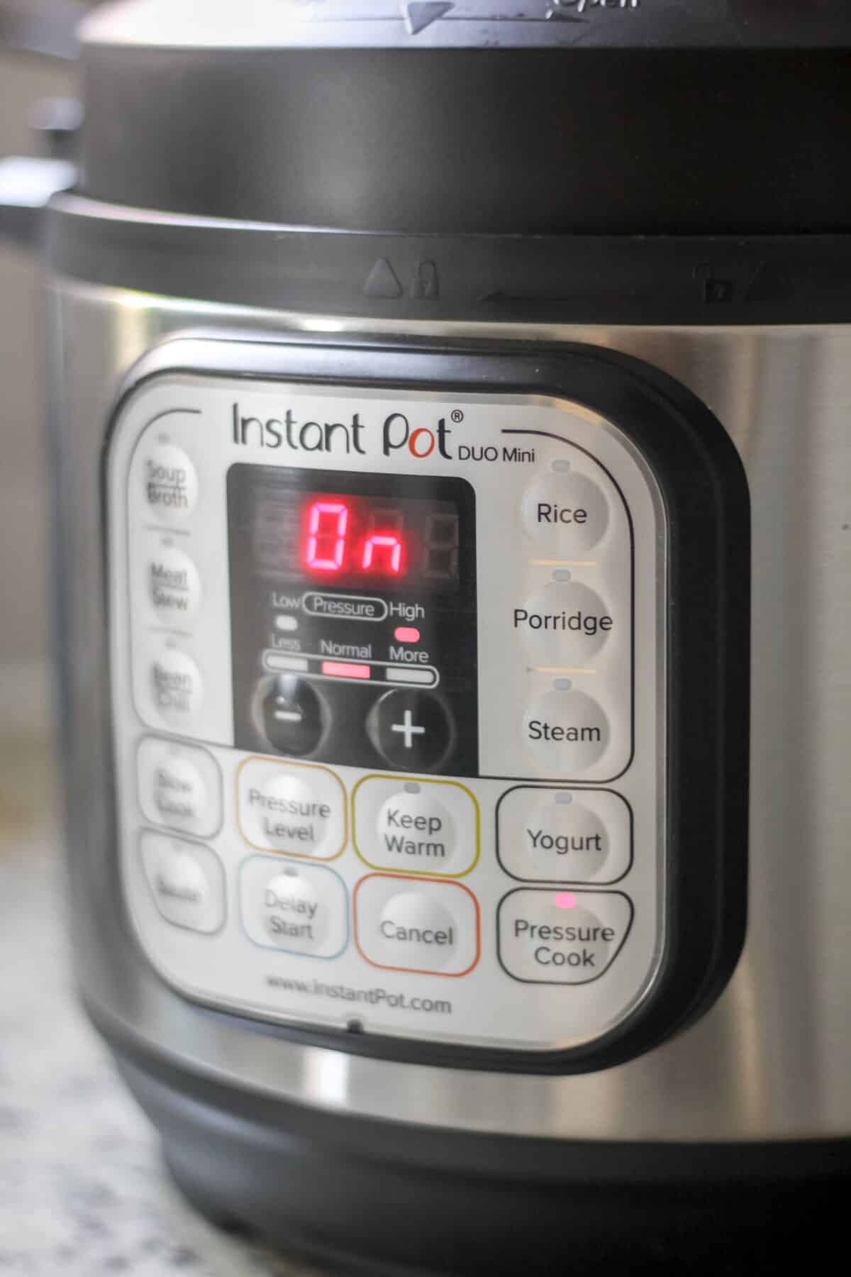 Close-up of an Instant Pot display showing it turned on and set to cook.
