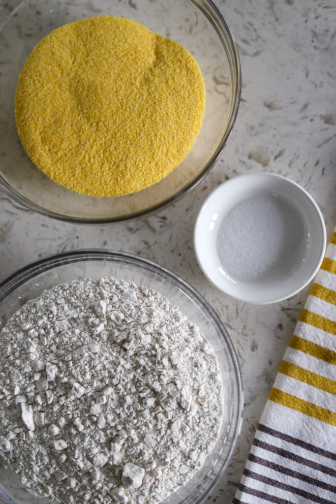 Ingredients set out: bowls of flour, cornmeal, and salt with a striped towel.