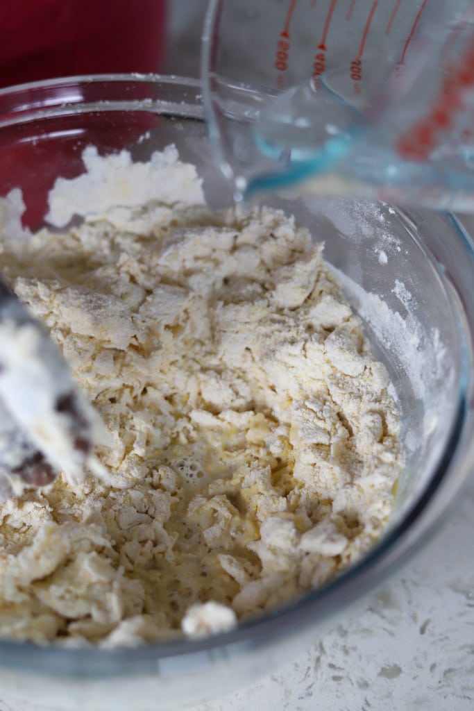 Mixing bowl with flour and cornmeal starting to come together with water.