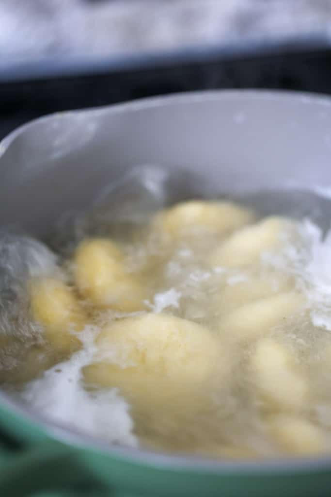 Cornmeal dumplings boiling in a pot of water.