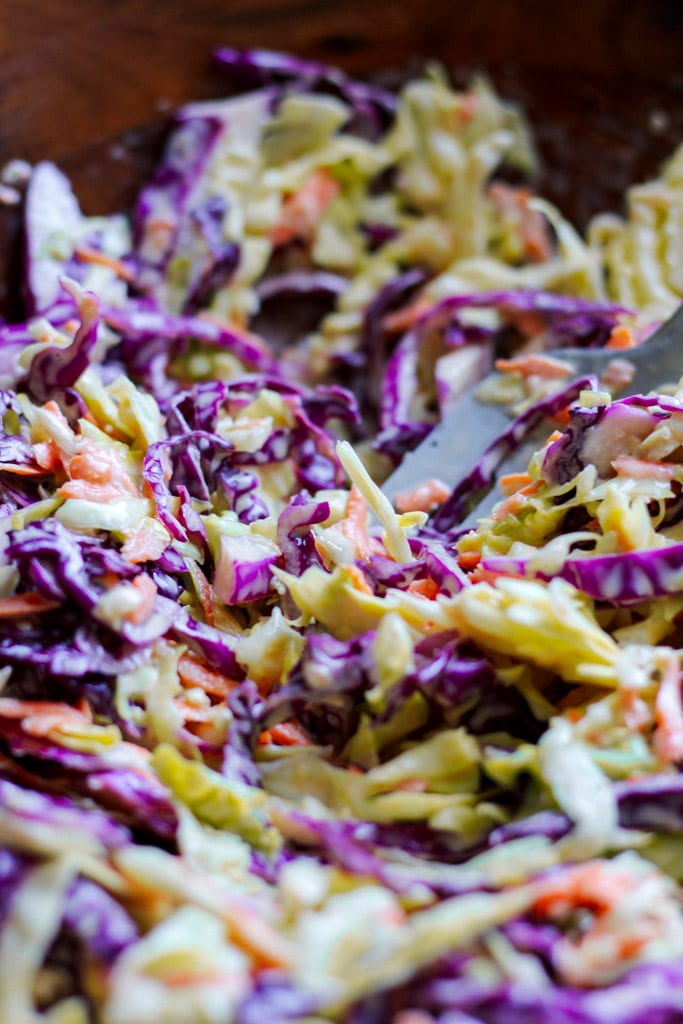 Close-up of creamy coleslaw with shredded green cabbage, purple cabbage, and carrots.
