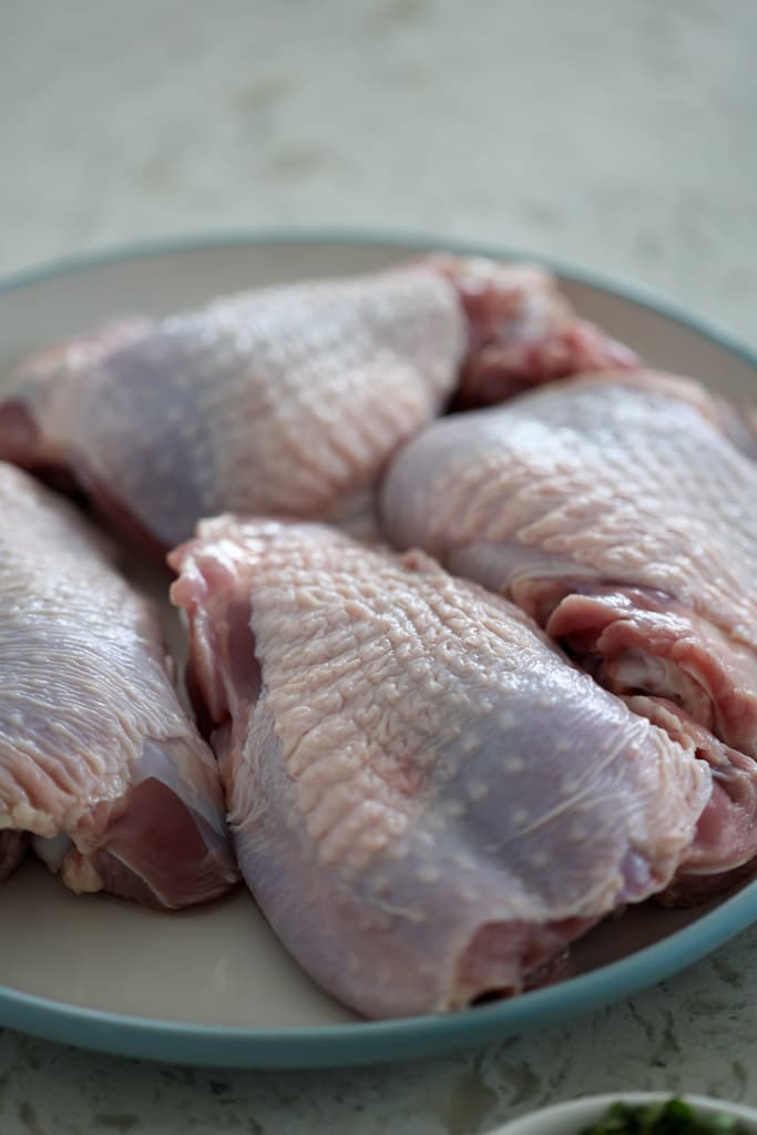 Raw turkey thighs on a plate ready to be seasoned.