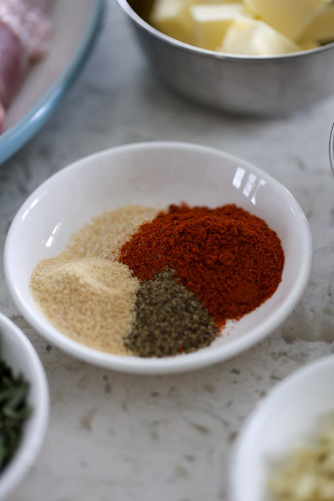 A bowl of paprika, onion powder, garlic powder, and black pepper for seasoning.