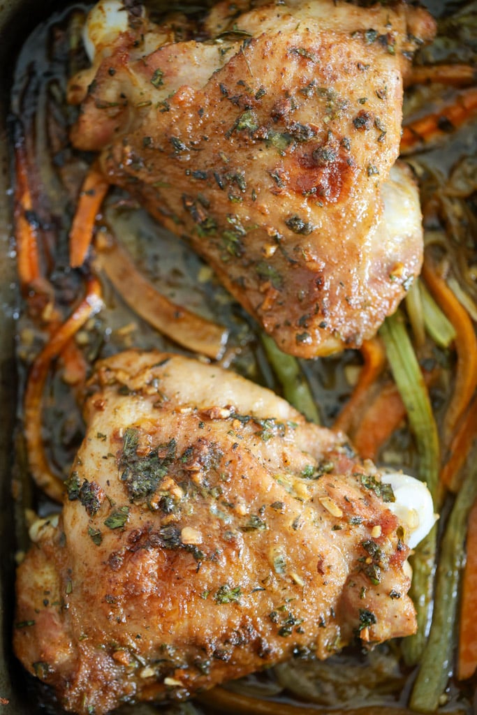 Overhead view of roasted turkey thighs with browned skin and vegetables underneath.
