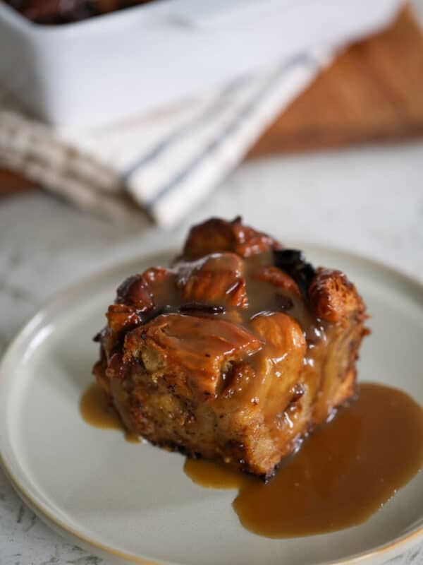A plated serving of bread pudding drizzled with rum sauce.