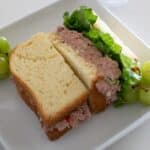 Half of a corned beef sandwich with lettuce on a plate beside green grapes.
