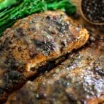Close-up of glazed honey jerk salmon fillets beside broccolini.